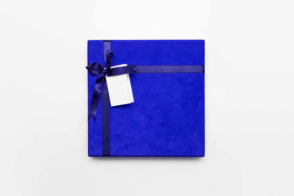 Blue velvet square gift box with dark blue ribbon bow, white background